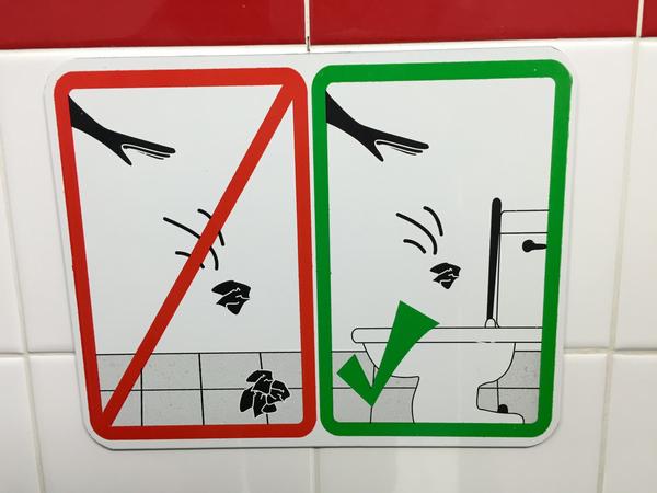 Bathroom sign warning not to throw toilet paper on the floor
